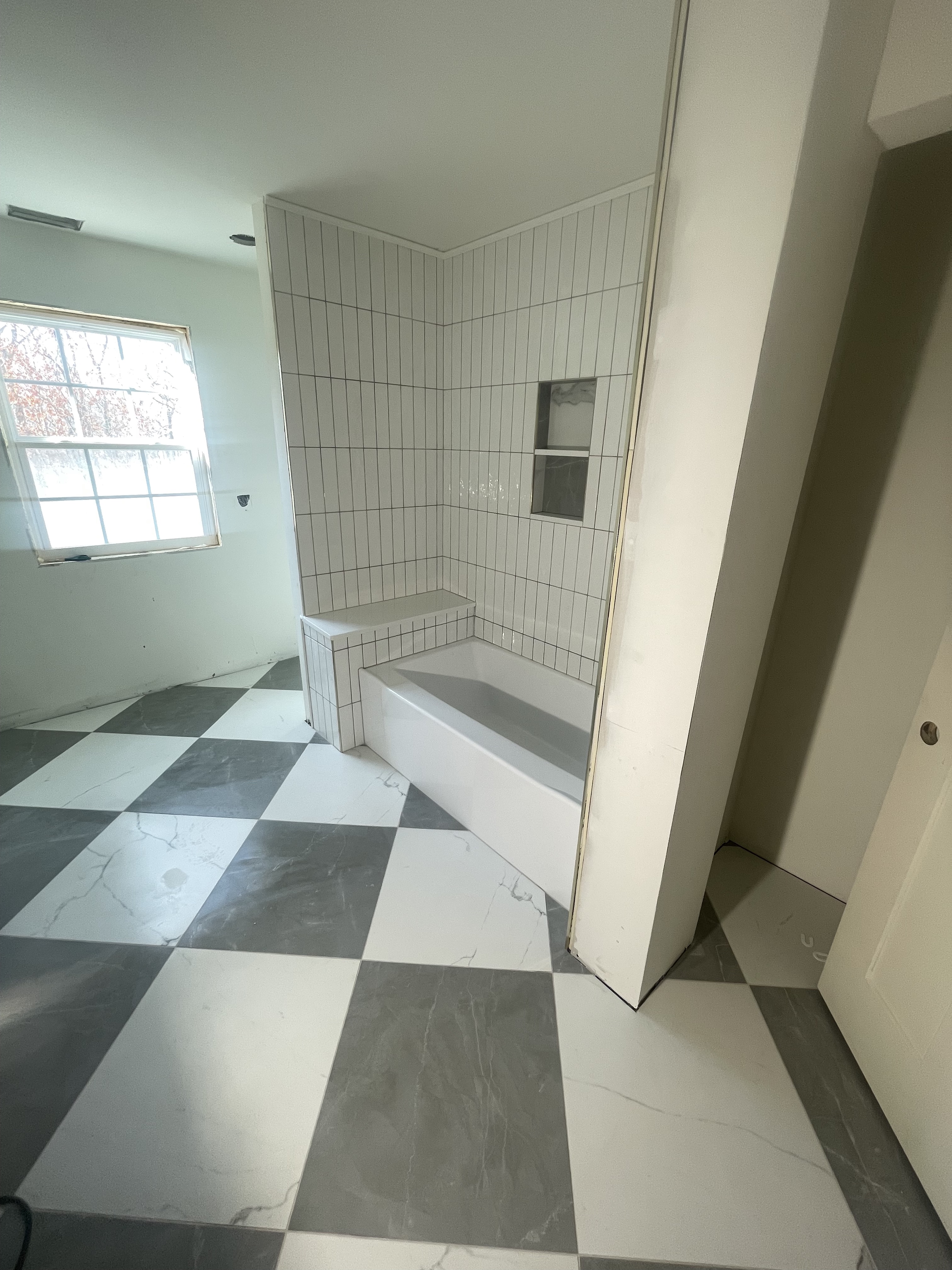 Checkerboard floor with tub and tiled shower
