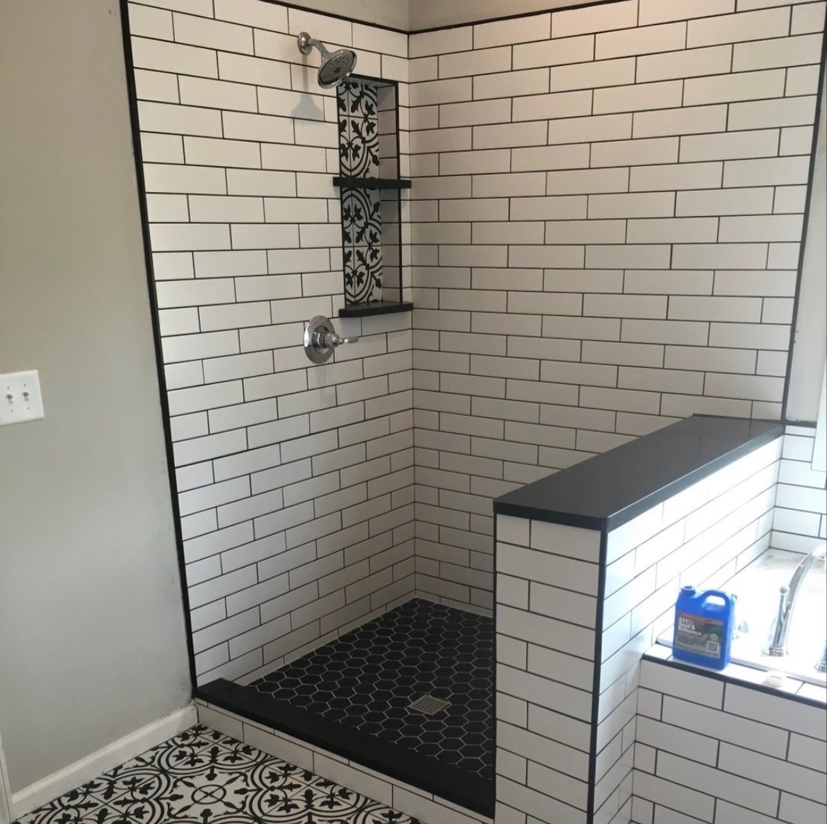 Subway tile shower with black tile floor and bench