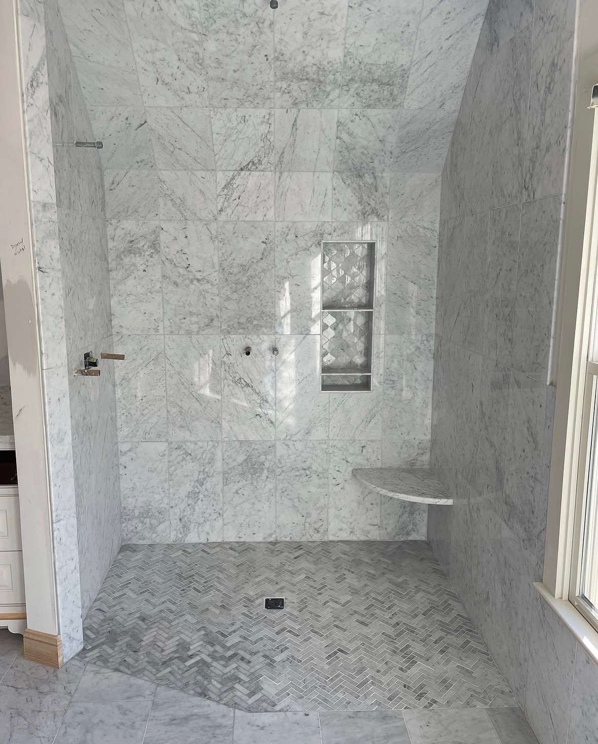Marble shower with herringbone floor and bench