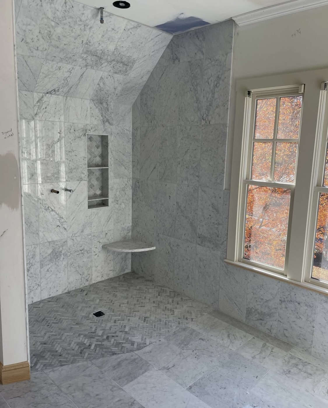 Marble shower with vaulted ceiling and herringbone floor